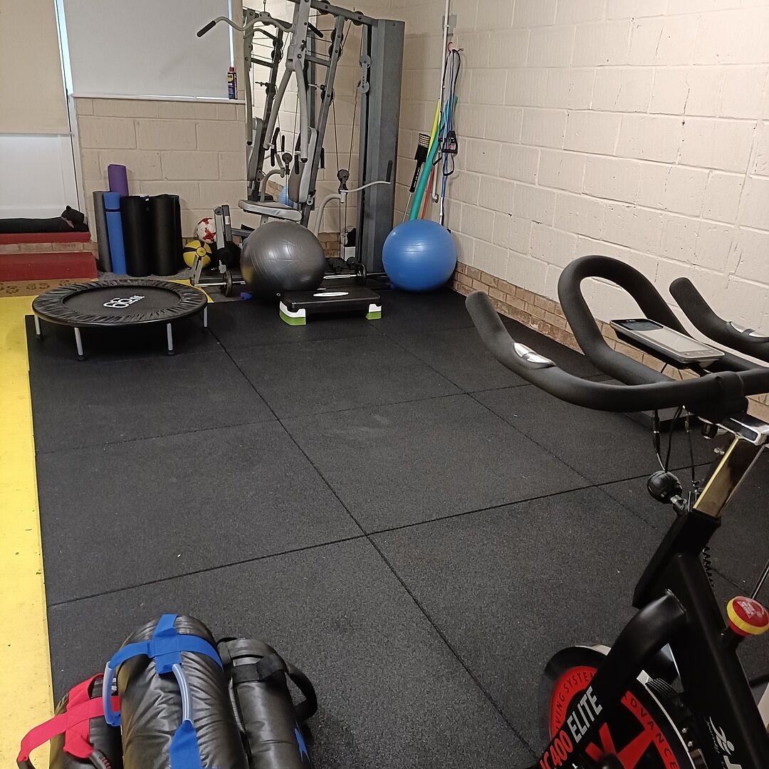 Black rubber tiles fitted beneath exercise equipment in Reggie’s training space.